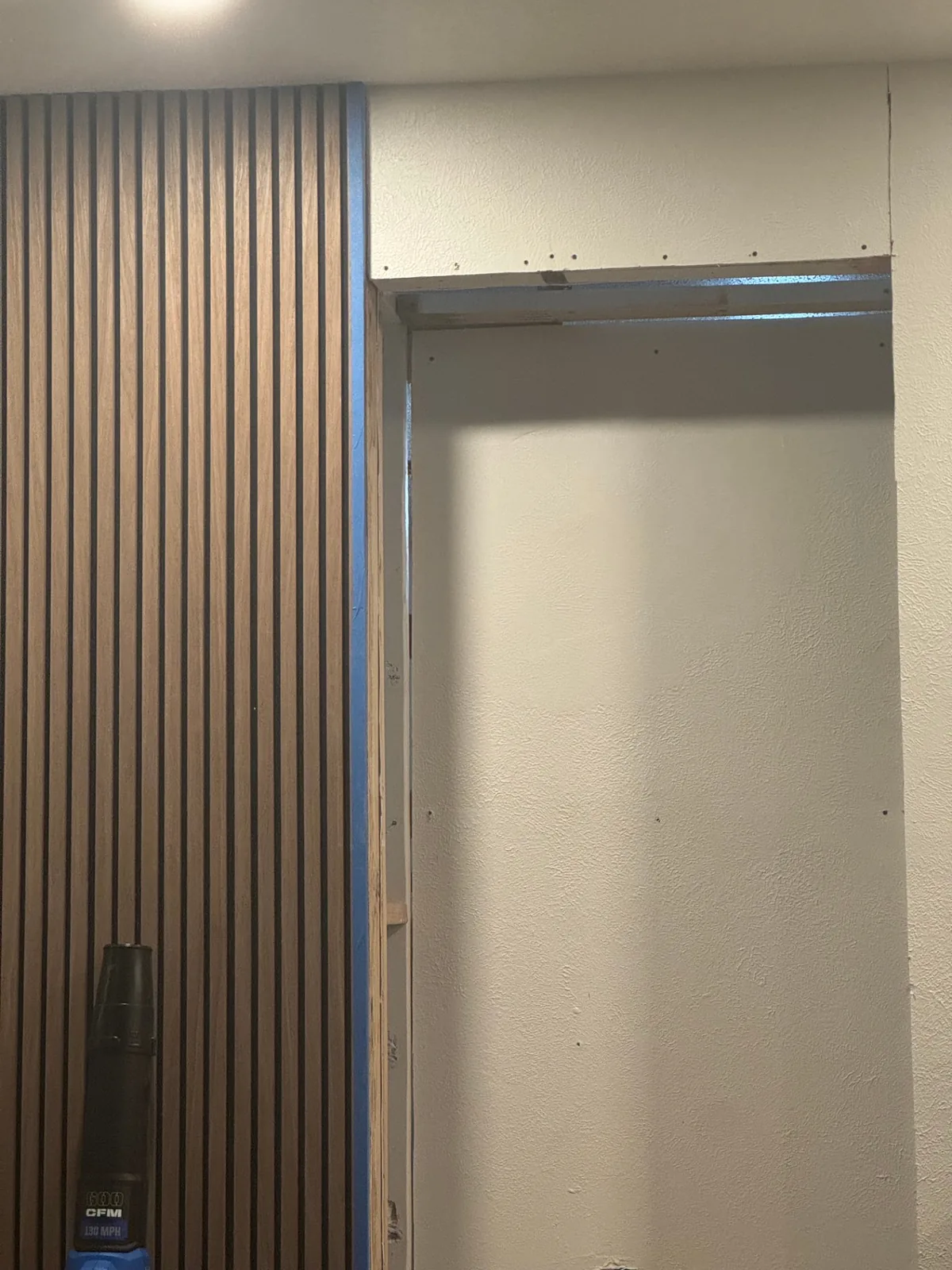 Entryway wood-slat finish installation in progress.